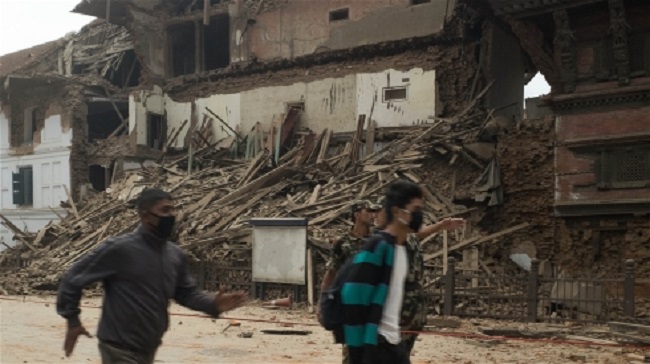 Men run past a collapsed building in Basantapur in central Kathmandu during an aftershock